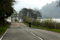 Cyclists on a road in the Scottish Highlands with a lake next to