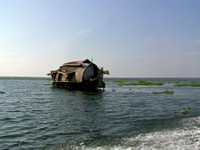 A houseboat moving placidly through a coastal lagoon in Alleppey