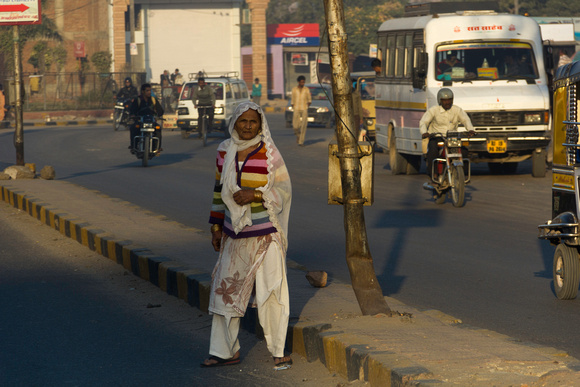 An old lady crossing the street in Jodhpur with regular traffic