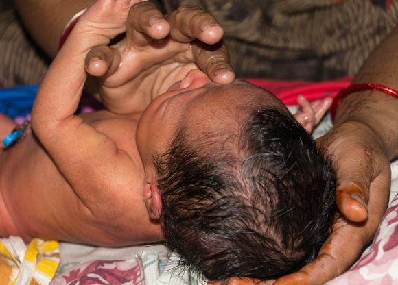 Masseuse doing light massage of eyes of a 5 day old Indian baby