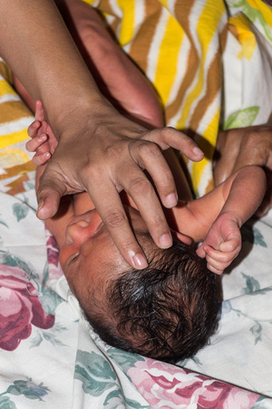 Masseuse doing light massage of forehead of a 5 day old Indian b